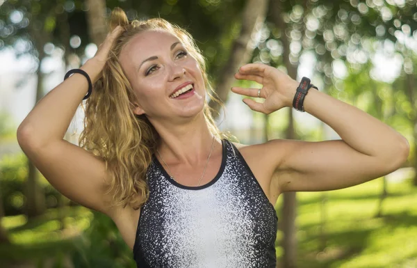 Blond girl, wears sportswear and exercises in the garden