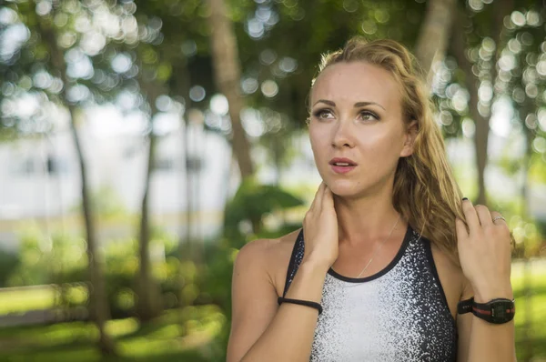 Blond girl, wears sportswear and exercises in the garden