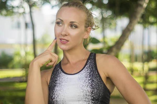 Blond girl, wears sportswear and exercises in the garden