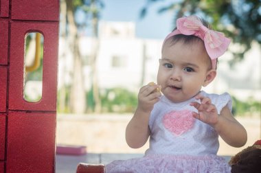 Bir yaşında bebek, sarı salıncak ve pembe fiyonk