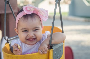 Bir yaşında bebek, sarı salıncak ve pembe fiyonk