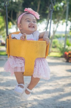 Bir yaşında bebek, sarı salıncak ve pembe fiyonk