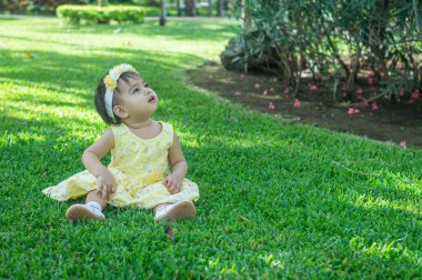 Çimenlerdeki küçük kız sarı elbise çiçekli saç bandı