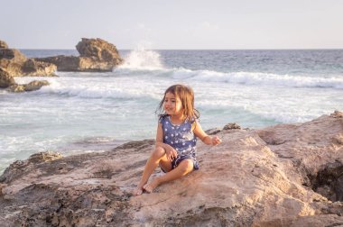Karayip denizinde bir kayanın üzerinde üç yaşında bir kız.