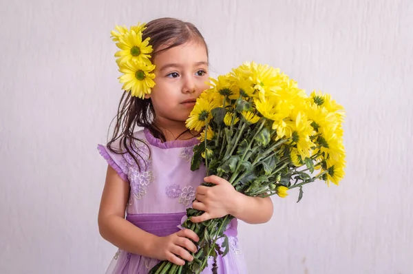 Dívka se žlutými květy ve vlasech a kytice — Stock fotografie