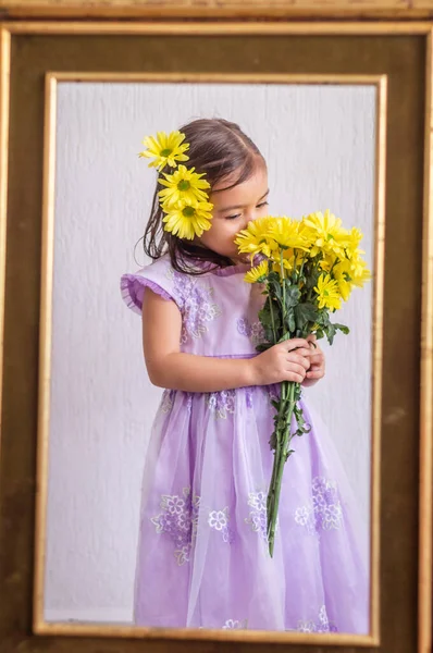 Маленькая девочка с желтыми цветами в старой рамке — стоковое фото