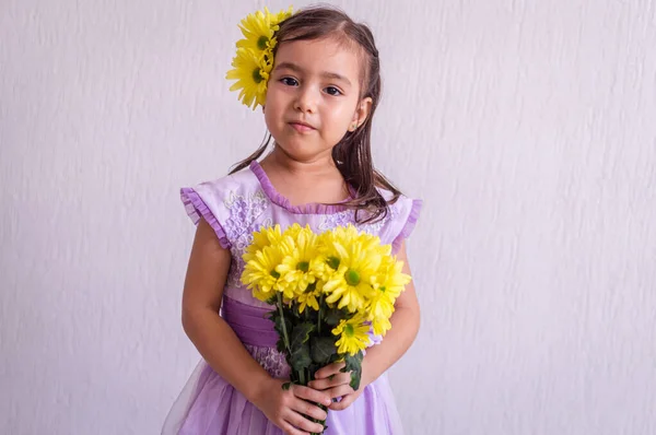 Menina macia, vestido violeta e flores amarelas — Fotografia de Stock