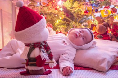 Beyaz elbiseli uyuyan bebek ve Noel ağacı