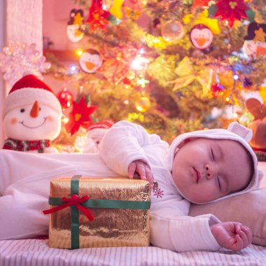 Beyaz elbiseli uyuyan bebek ve Noel ağacı