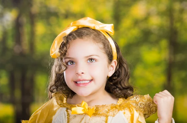 可爱的小女孩穿着漂亮的黄色衣服配头乐队合影相机，绿色森林背景 — 图库照片