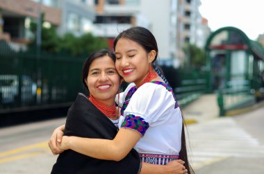 Güzel İspanyol anne ve kızı geleneksel And giysileri giyen, birlikte kucaklayan, mutlu, açık havada çevre kamu istasyonunda otobüs beklerken