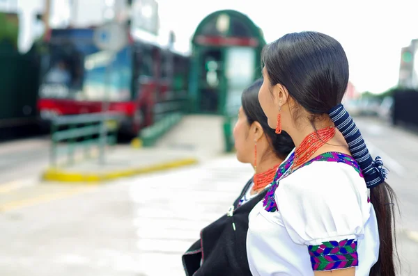 Bella madre e figlia ispanica indossa abiti tradizionali andini, in attesa di autobus alla stazione pubblica, mentre in piedi insieme, come si vede dal profilo, all'aperto ambiente — Foto Stock