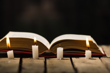 Kalın kitap ahşap yüzeyde, balmumu açık yalan önde yerleştirilmiş, güzel gece lambası sihirli kavramı ateş ayarlama, mumlar