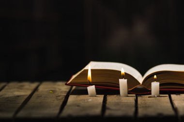 Kalın kitap ahşap yüzeyde, balmumu açık yalan önde yerleştirilmiş, güzel gece lambası sihirli kavramı ateş ayarlama, mumlar