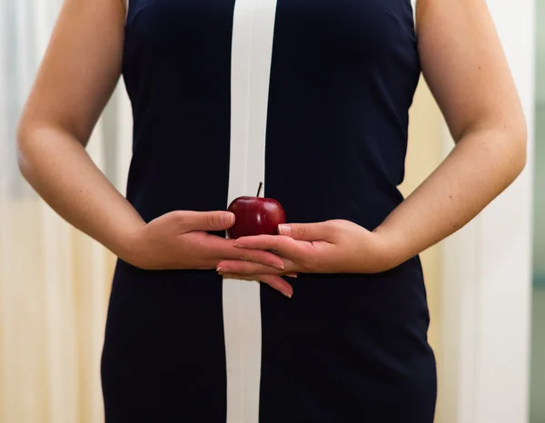 Closeup womans stomach wearing blue dress, holding apple between hands, weightloss concept — Stock Photo, Image
