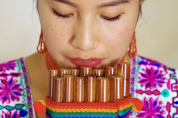 Gros plan de jeune jolie femme portant de beaux vêtements traditionnels andins, assise avec tout en jouant de l'harmonica — Photo