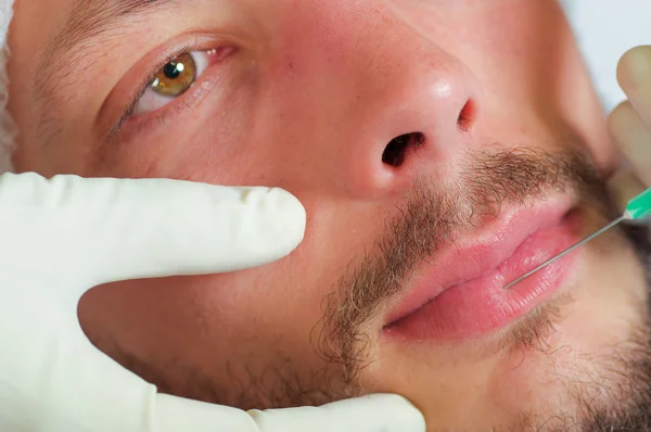 Primer plano cara de los hombres jóvenes que reciben inyecciones de tratamiento cosmético facial, los médicos mano con el guante que sostiene la jeringa —  Fotos de Stock