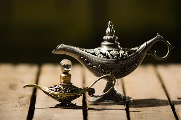 Красивая антикварная металлическая лампа в истинном стиле Аладина, меньшая модель размещена рядом с ней, сидя на деревянной поверхности — стоковое фото