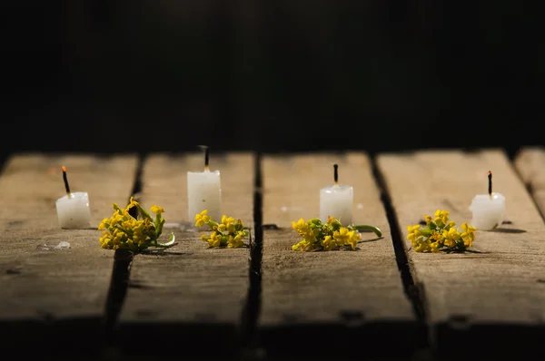 Quatro velas de cera branca sentadas na superfície de madeira, sem chamas queimando, com fundo preto, belo cenário de luz — Fotografia de Stock