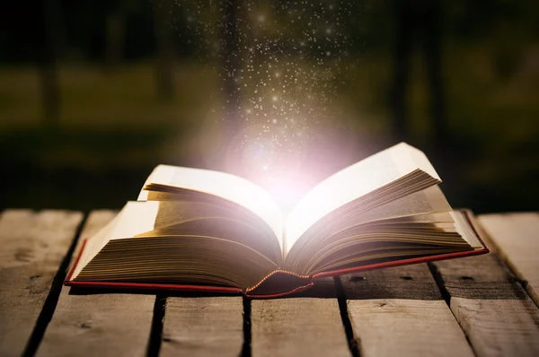 Ahşap yüzey, sihirli yıldız tozu, güzel bir gece ışık ayarı, sihirbaz kavram ateş çıkan açık yatan kalın bir kitap — Stok fotoğraf