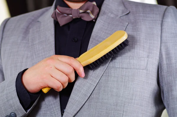 Closeup mans chest area wearing formal suit and bowtie, brushing off jacket using brush, men getting dressed concept — Stock Photo, Image