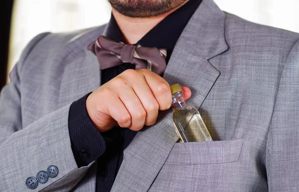 Zbliżenie Mans obszar klatki piersiowej ubrany w formalne garnitur i krawat, umieszczając małą butelkę alkoholu w kieszeni kurtki, mężczyźni coraz ubrany pojęcie — Zdjęcie stockowe
