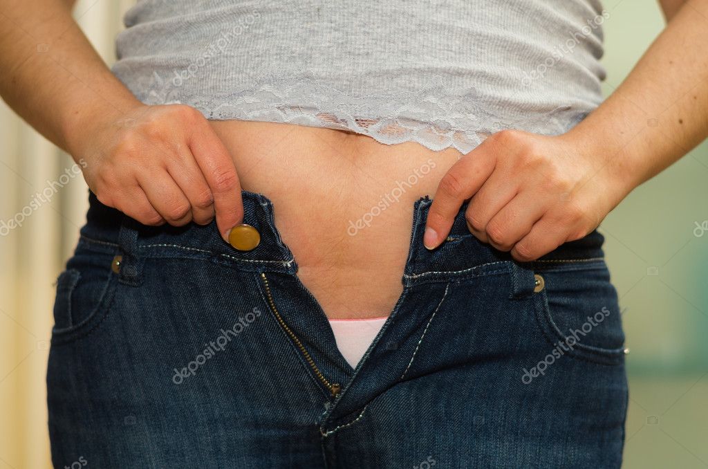 Closeup stomach woman with jeans unzipped, hands holding onto