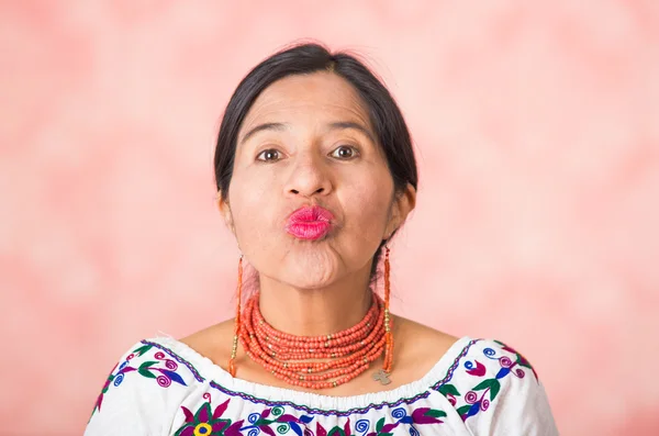 Headshot mooie Spaanse moeder het dragen van traditionele Andes kleding, waardoor kussen lippen op de achtergrond van de studio van de camera, roze — Stockfoto