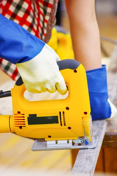 Female carpenter cutting wood with an electrical jigsaw — Stock Photo, Image