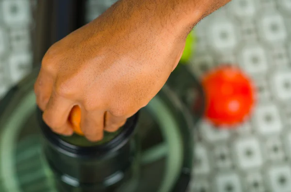 Closeup mans hands using juice maker, inserting carrot into machine, healthy lifestyle concept — Stock Photo, Image