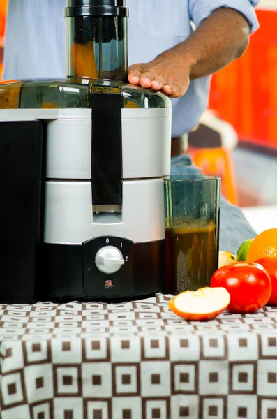 Primo piano mani mans utilizzando succo maker, inserendo carota in macchina con ciotola liquida arancione collegato, concetto di stile di vita sano — Foto Stock