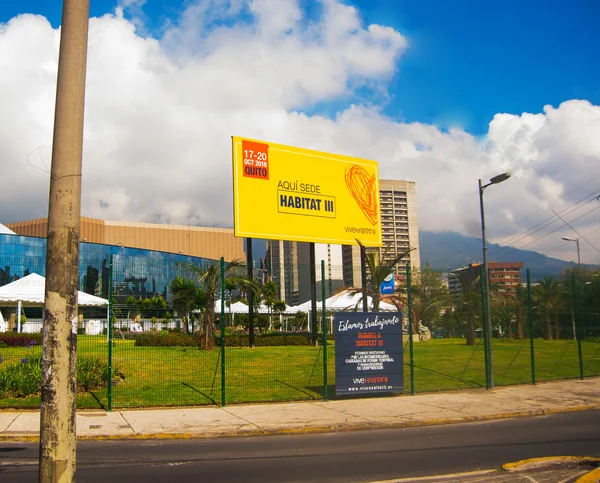 QUITO, ECUADOR - 8 DE OCTUBRE DE 2016: Zona exterior a Casa de la cultura, sede de la tercera conferencia de Hábitat de las Naciones Unidas, gran cartel amarillo anunciando el evento actual, bonito cielo azul — Foto de Stock