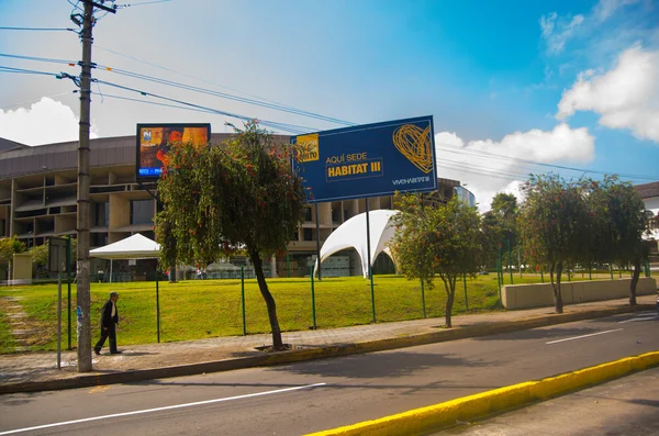 QUITO, ECUADOR-8 OUTUBRO, 2016: Casa de la cultura, local da terceira conferência Habitat das Nações Unidas, vista de fora da arena com grande sinal anunciando o evento atual, belo céu azul — Fotografia de Stock