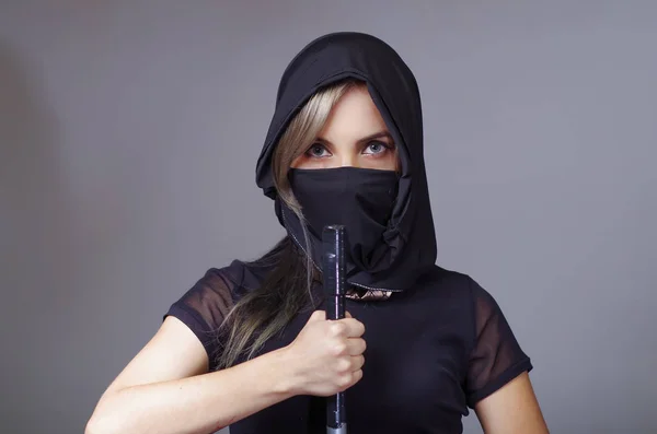 Samurai vrouw gekleed in het zwart met bijpassende sluier die betrekking hebben op gezicht, die hand op de tegenoverliggende camera zwaard, ninja concept — Stockfoto