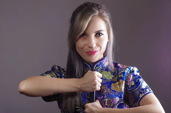 Samurai-Frau in traditionellen bunten Blumenmuster asiatischen Seidenkleid gekleidet, hält Hand auf Schwert vor der Kamera, Ninja-Konzept — Stockfoto