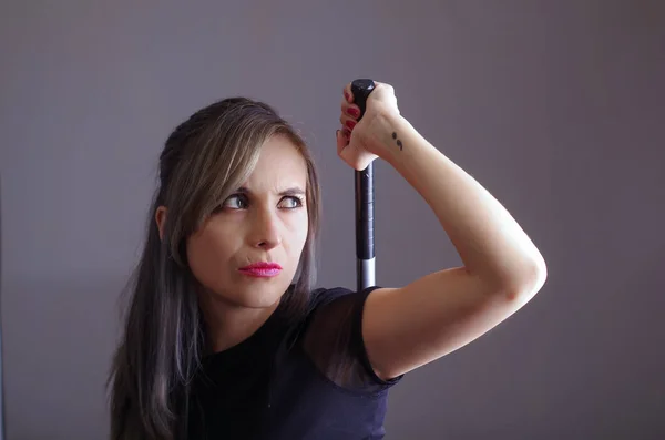 Samurai woman dressed in black clothes holding arm over shoulder grabbing sword hidden behind back, facing camera, ninja concept — Stock Photo, Image