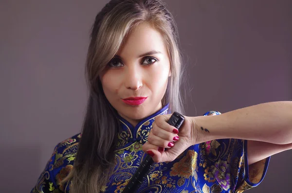 Samurai mulher vestida em tradicional colorido flor padrão asiático vestido de seda, segurando a mão na espada enfrentando câmera, conceito ninja — Fotografia de Stock