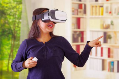 Geleceğin teknolojisi yaşıyor, etkileşim ve oynarken, iç arka plan, vr kavramı gülümseyen sanal gerçeklik giyen genç esmer kadın gözlüğü