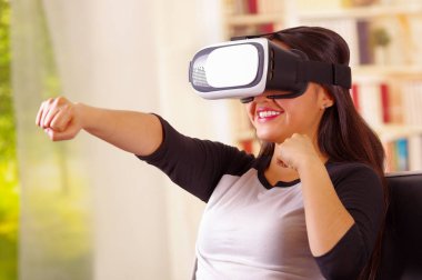 Geleceğin teknolojisi yaşıyor, etkileşim ve oynarken, iç arka plan, vr kavramı gülümseyen sanal gerçeklik giyen genç esmer kadın gözlüğü