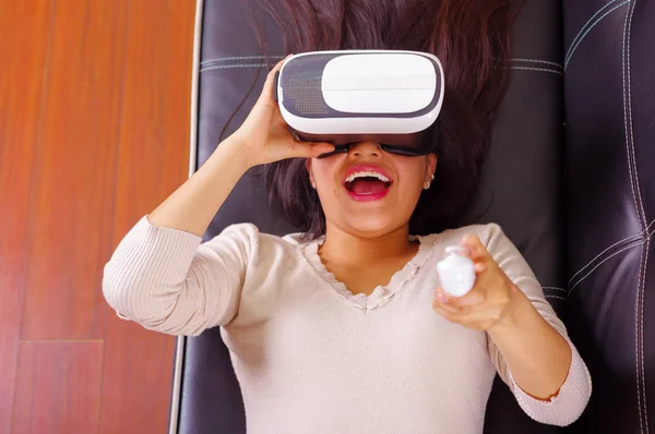 Joven morena acostada usando gafas de realidad virtual experimentando tecnología futura, interactuando y sonriendo mientras juega, vr concepto , —  Fotos de Stock