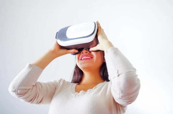 Mujer morena joven con gafas de realidad virtual experimentando la tecnología del futuro, interactuando y sonriendo mientras juega, fondo de estudio, concepto vr —  Fotos de Stock