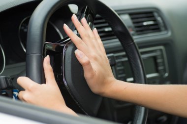 Araç Direksiyon simidinde honking boynuz, siyah iç arka plan, kadın sürücü kavram iterek el içinde closeup