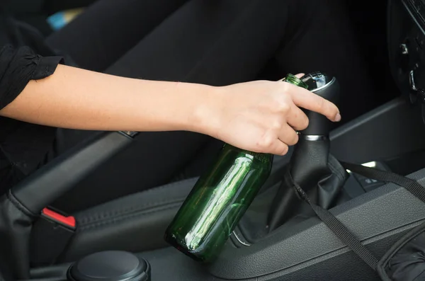 Fechar dentro do veículo de mão segurando em garrafa de cerveja verde e mudança de vara, fundo interior preto, conceito de motorista feminino — Fotografia de Stock