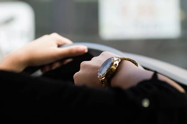 Крупный план внутри автомобиля женской руки, держась за руль, другая рука, показывающая наручные часы, женская концепция водителя — стоковое фото