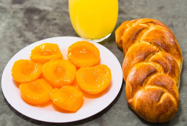 Närbild nybakat sockerbröd med vacker gyllene färg, vit platta av skivade persikor, bagerikoncept — Stockfoto
