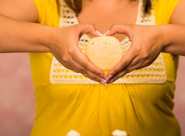 Kvinna med cirkulär gyllene färgade cookie visar till kameran, konditorivaror koncept — Stockfoto