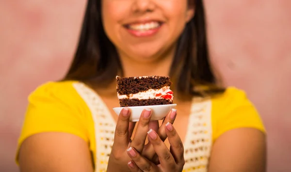 Mujer morena sosteniendo delicioso pedazo de pastel de chocolate con relleno de crema, gran sonrisa y listo para tomar un bocado, concepto de pastelería —  Fotos de Stock