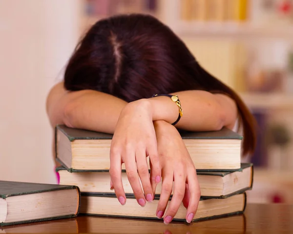 Giovane donna bruna sdraiata su una pila di libri, sembra essere addormentato, concetto di studente stanco — Foto Stock