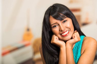 Güzel esmer fotoğraf makinesi, doğal gülümseme ile poz baş eller üzerinde dinlenme