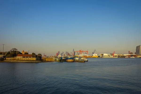 Shanghai, China: Shanghai riverbank, industriële boten en sommige havenfaciliteiten liggen aan het water, mooie blauwe hemel — Stockfoto